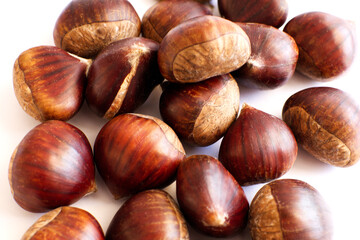 Pile of fresh sweet chestnuts isolated on white background. Chestnuts for roasting.