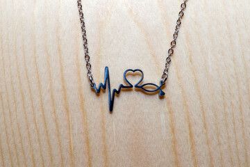 pendant cardiogram, heart, stethoscope on a chain on a wooden background. decoration for doctor...