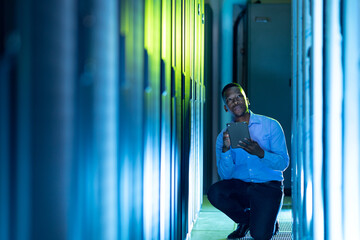 African american male computer technician using tablet working in server room