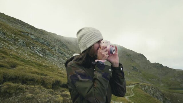 person in the mountains taking a picture with a polaroid camera