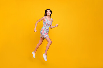 Full length body size woman smiling jumping high happy running fast cheerful isolated vivid yellow color background