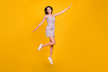 Fototapeta na wymiar Full length body size woman smiling jumping high happy playful overjoyed isolated vivid yellow color background