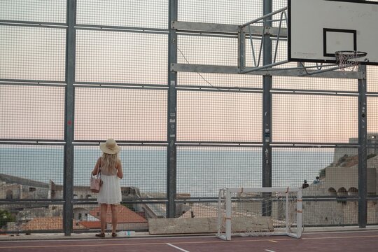 Young traveler girl on basketball court inside the fortress in Dubrovnik, Croatia. Popular tourist destination in Croatia, Dubrovnik tourists take pictures of medieval fortification. Travel to Croatia