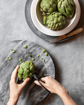 Removing the thorns from the leaf ends to prepare an artichoke for steaming