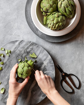 Trimming the top of an artichoke in preparation for steaming