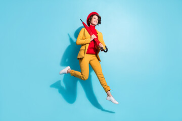Fototapeta na wymiar Photo of sweet charming woman dressed red jumping holding parasol looking empty space smiling isolated blue color background