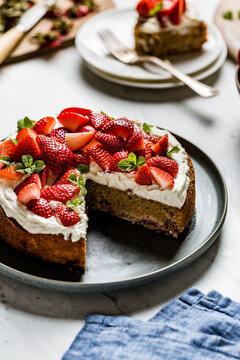A homemade strawberry cake on a black plate and marble worktop. Made with almond flour.