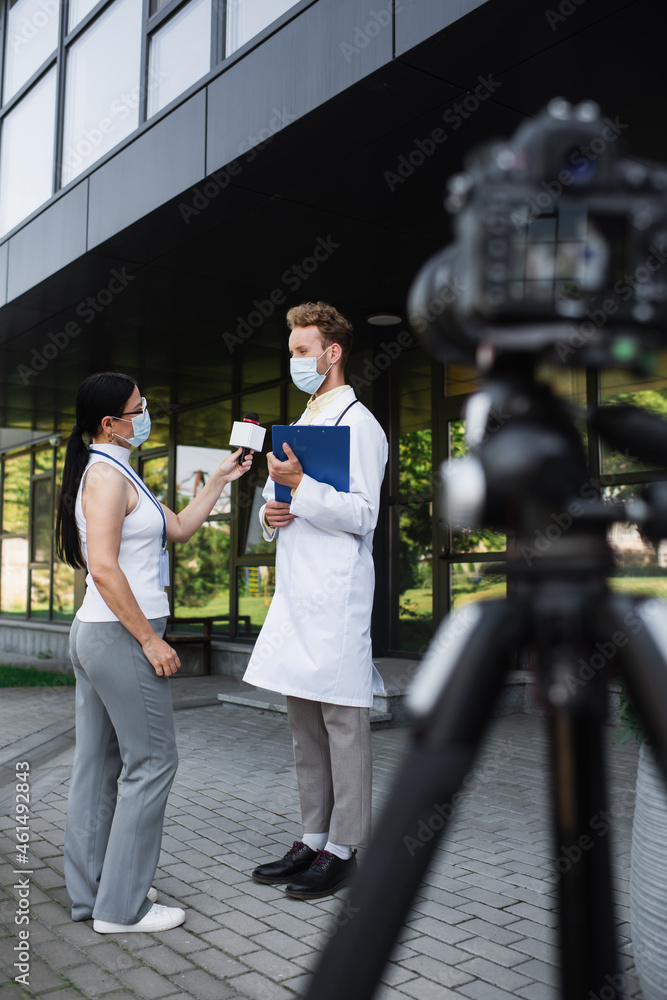 Canvas Prints asian reporter holding microphone near doctor in medical mask giving interview near blurred digital camera