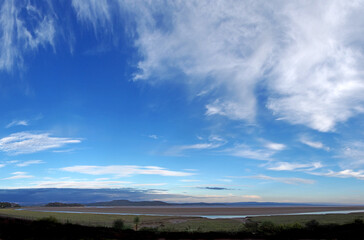 Fototapeta premium panoramic view of the coast at grange over sands in cumbria at twilight with grass covered wetland in the foregrounds and the north lakes area in the distance