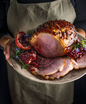 Gammon, sliced and served on a plate with garnish. Held by a woman chef.