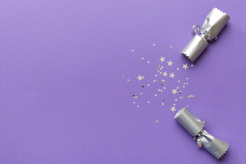 Christmas crackers with shiny confetti on color background, top view, copy space