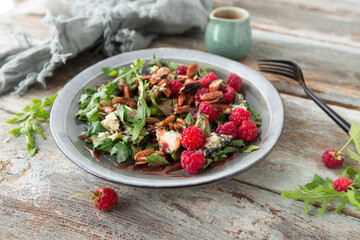 a plate with arugula, gorgonzola and raspberry salad on a wooden table close-up