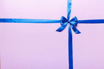 Top view of blue ribbon rolled and blue bow isolated on colored background. Flat lay with copy space