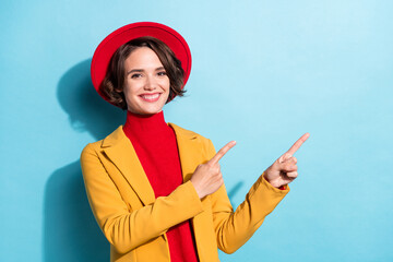 Photo of sweet charming young woman dressed red headwear pointing fingers empty space isolated blue...