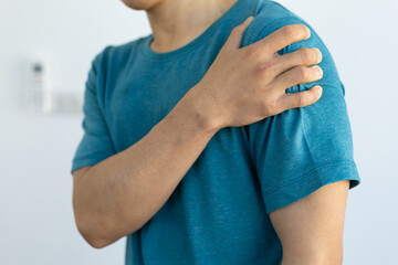Close-up of a man with pain in his shoulders and arms.