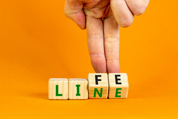 Lifeline, line of life symbol. Businessman hand turns cubes and changes the word 'life' to 'line'. Beautiful orange background. Business lifeline, line of life concept. Copy space.