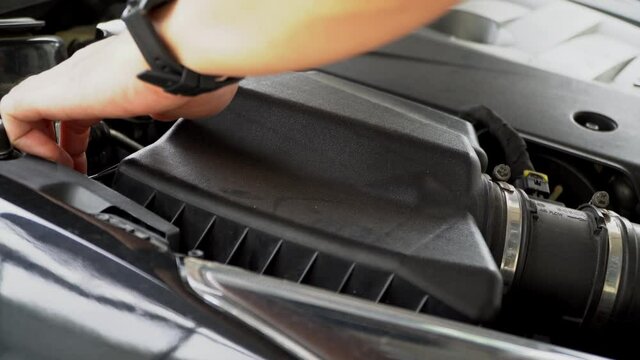 Asian mechanic checks the car air filter to the filter socket of the car engine. automotive parts concept
