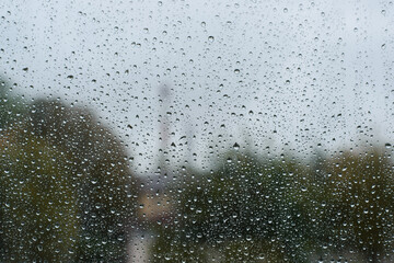 Cloudy rainy day. Raindrops on surface of window, texture background, copy space. Bad weather concept