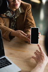 cropped view of blurred announcer pointing at smartphone near colleague