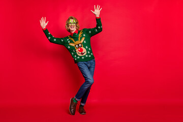 Photo of impressed funny young man wear green sweater spectacles smiling dancing empty space isolated red color background