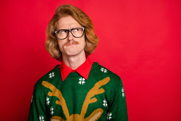 Photo of doubtful unsure young man wear green sweater spectacles looking empty space isolated red color background