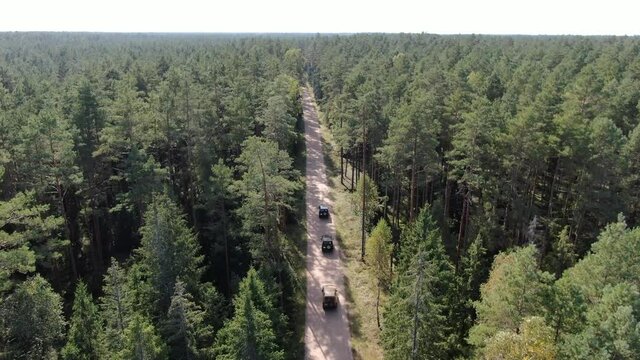 Drone following three 4x4 off-road cars in a forest