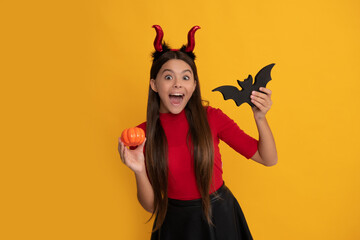 celebrate autumn party holiday. childhood fun. amazed evil child in imp horns hold bat