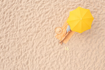 Woman resting under yellow beach umbrella at sandy coast, aerial view. Space for text
