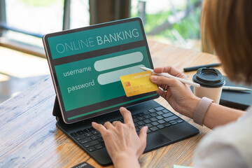 Asian woman and holding bank credit card for payment on laptop for online shopping sitting in modern cafe.