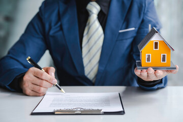 Real estate agent home sales broker is using a pen pointing to the house model and explains the business contract, rent, buy, mortgage, loan, or home insurance