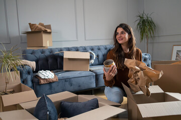 Smiling woman unwrapping and unpacking belongings in her new home.