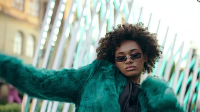 Young attractive woman with curly hair dancing rnb outdoor, stylish clothes