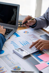 Two business people working together to analyze, work together to discuss company financial statistics, brainstorm ideas, and graph documents on the table.
