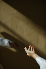 two lover reaching hands at the shadows of the sun in the morning