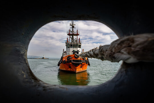 Tug boat pulling ship with rope.