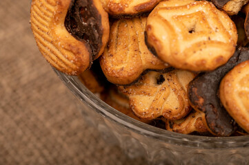 Curly cookies covered with chocolate icing in a glass vase, close-up, selective focus.