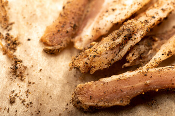 thinly sliced homemade lard with pepper on white oiled paper, close-up, selective focus.