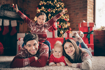 Photo of four people have noel fun lay floor enjoy miracle dream wear sweater in decorated x-mas home indoors