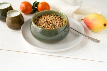 bowl with granola, jugs with yogurt and fresh tangerines on a white wooden table