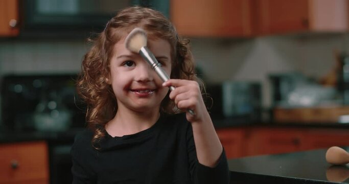 Cute toddler girl applying makeup by herself.