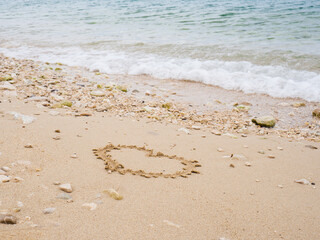 Hand writing heart shape on the beach