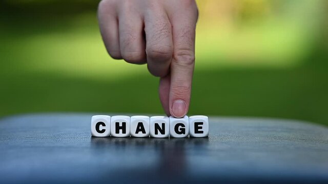 Hand is turning a dice and changes the word change to chance.