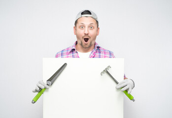 Surprised male gardener holding white board with gardening tools, isolated on white background....