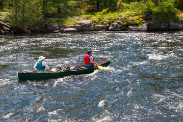 Fully loaded canoe, paddled by two people shoots a set of rapids on the French River, an historic...