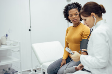 Woman having measured blood pressure by a doctor using sphygmomanometer.