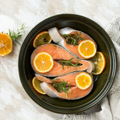 round baking sheet with salmon with rosemary and lemon on the table