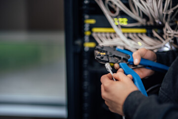 Technician holding hand crimping tool and ethernet cable.