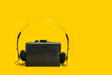 Walkman negro con auriculares sobre fondo amarillo. Vista de frente y de cerca. Copy space
