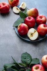 Fresh red apples with green leaves on a black background. Fruits. Top view, copy space.