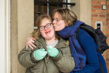 Portrait of a disabled smiling girl, kissed by her woman friend